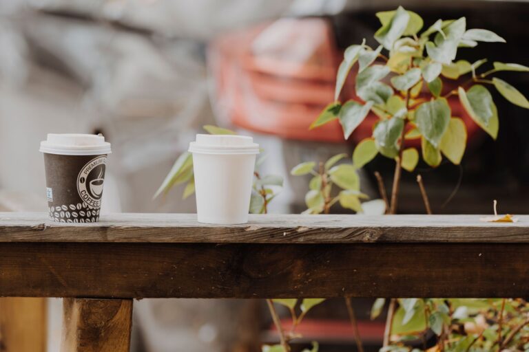 Două căni de cafea pe o măsuță de balcon, în lumina caldă a dimineții, sugerând o discuție liniștită
